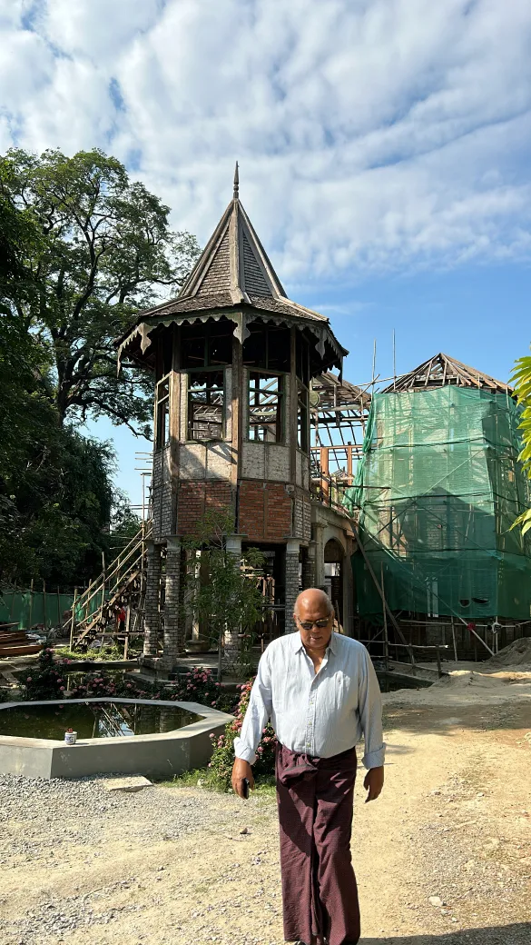 U Kyaw Sein walking on site in front of a restoration under scaffolding